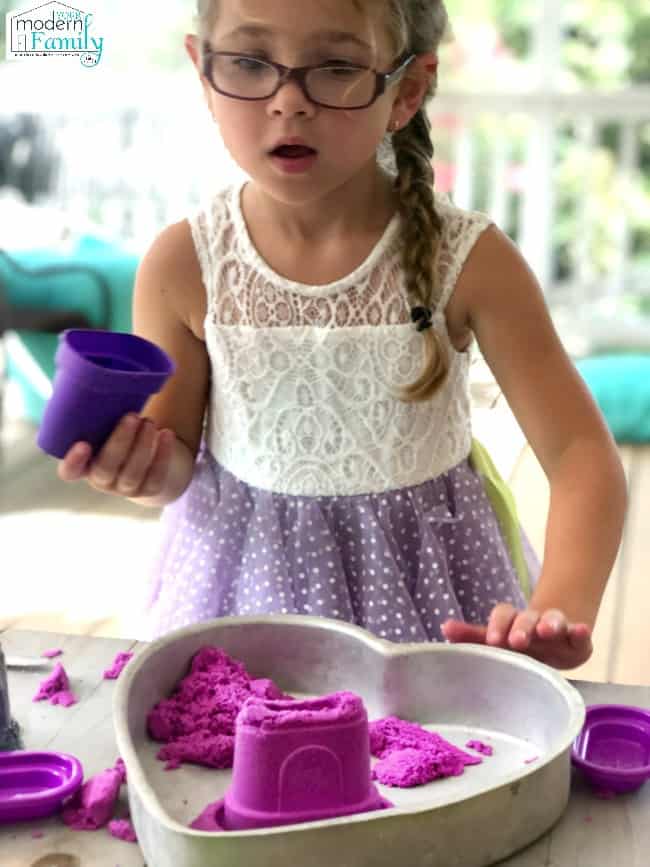 Child playing with kinetic sand and thinking putty