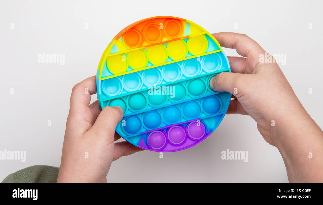 Close-up of a child's hands playing with colorful pop-it fidget toys and kinetic sand