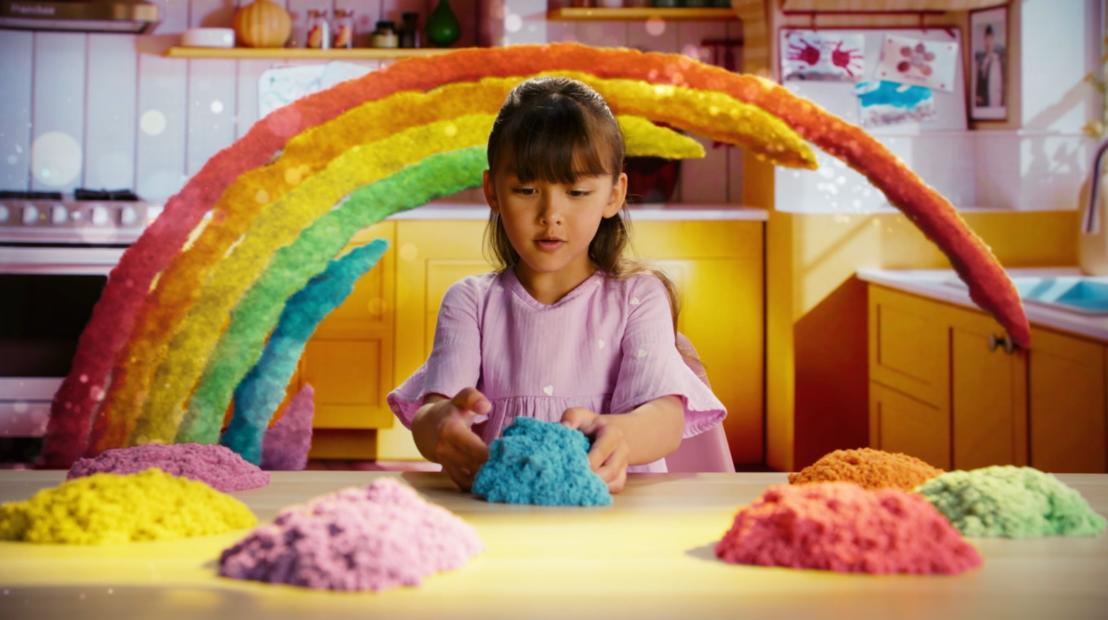A child's hands playing with colorful kinetic sand, shaping it into a castle