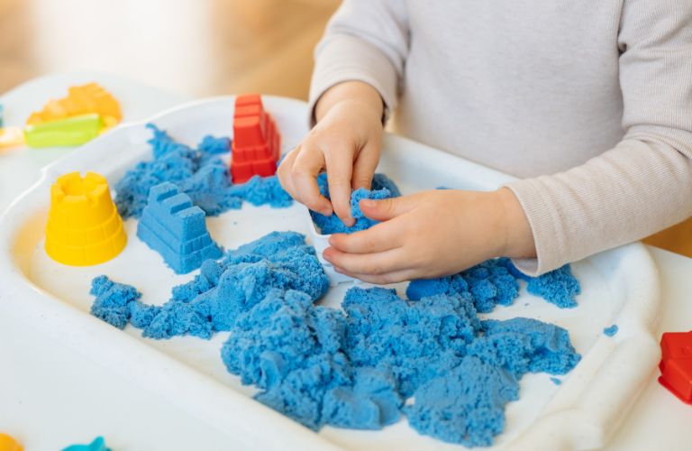 A teen's hands playing with colorful kinetic sand and slime
