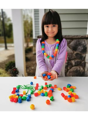 A child's hands threading large beads onto a string